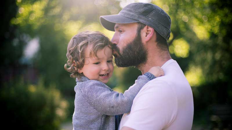 Padre besando a su joven hijo en la frente