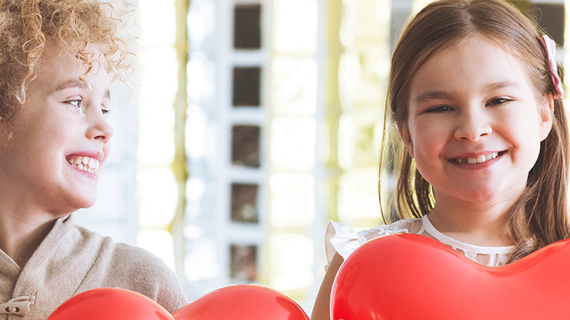 Two girls holding large red hearts