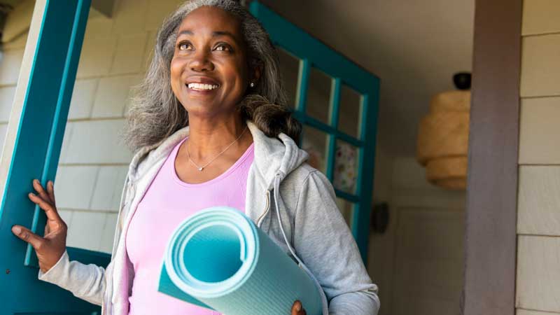 female leaving house with yoga mat