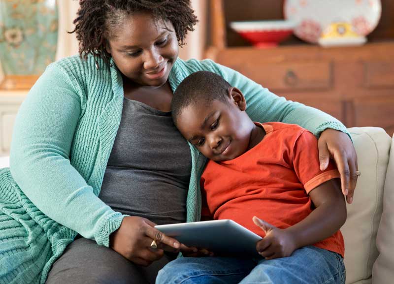 Mother and son on couch looking at tablet