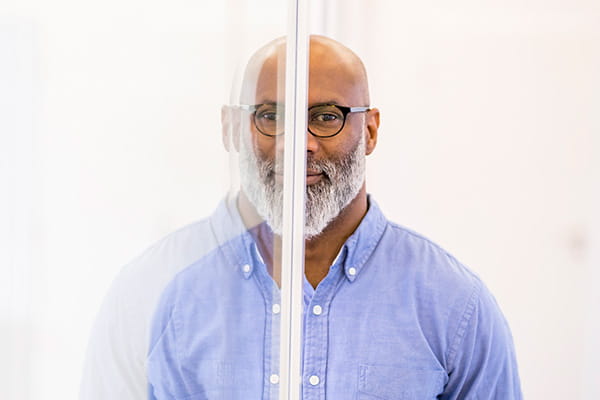 A bald middle-aged businessman and his mirror image on glass pane