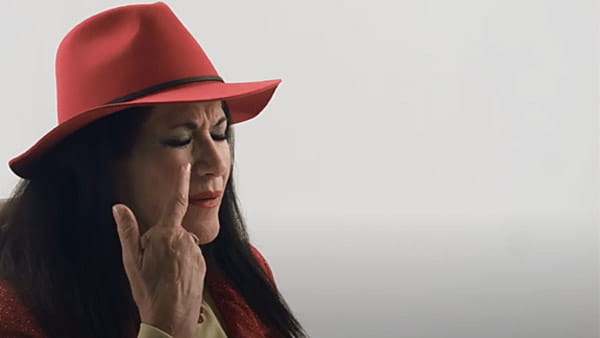 Una captura de pantalla de video de Claudia Montano, sobreviviente de ataque o derrame cerebral, apuntando a su ojo sobre un fondo neutro