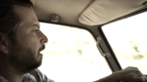 A video screen shot of stroke survivor, Stefan, a man with a beard driving a car
