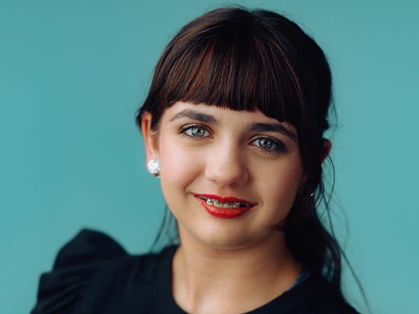 A professional headshot of Makenzie Childs on a turquoise background.