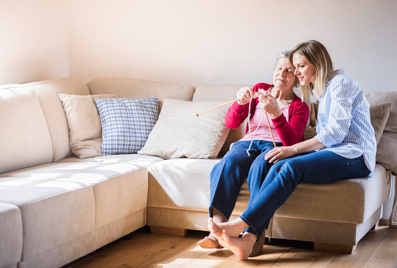 elderly woman and her adult granddaughter knitting