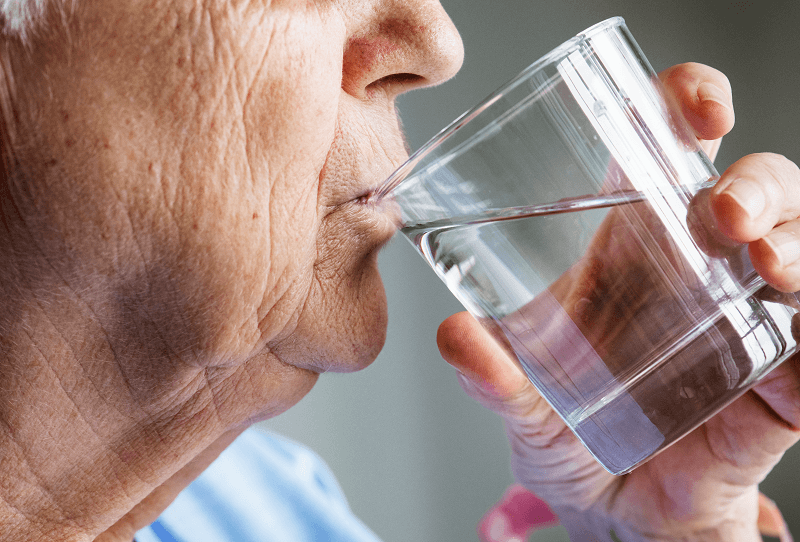 woman swallowing water from a glass