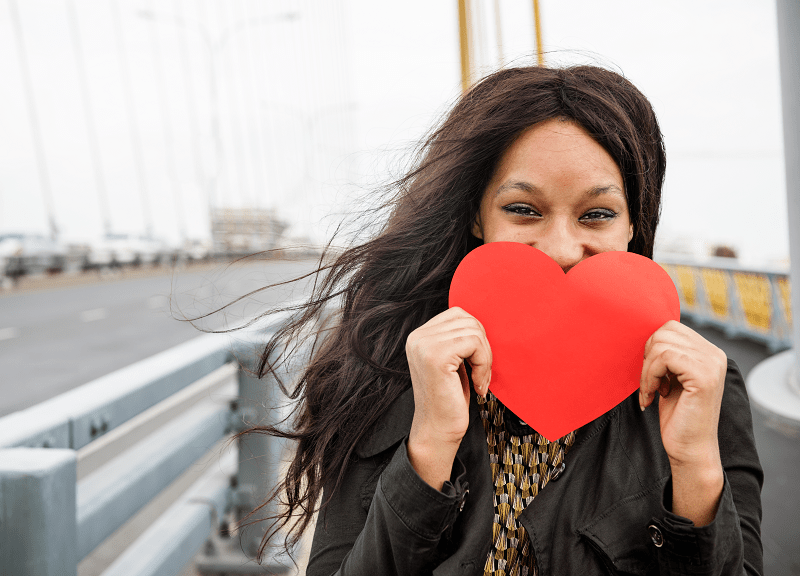 woman holding a red heart to her face
