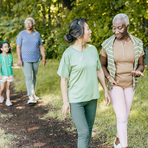 senior women hiking and talking on a dirt trail senior women hiking and talking on a dirt trail