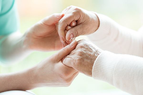 close up of a health care professional holding both hands of a senior patient close up of a health care professional holding both hands of a senior patient
