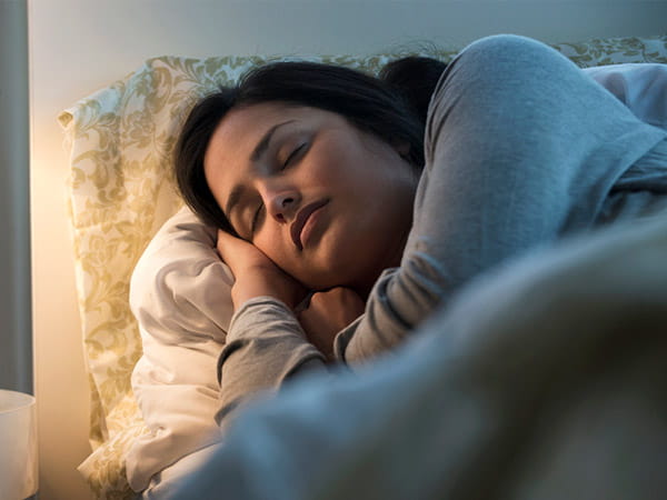 A Hispanic/Latina woman is sleeping in bed.