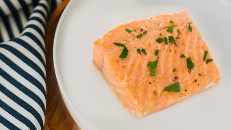 a salmon filet sprinkled with green herbs a salmon fillet sprinkled with green herbs is on a white plate