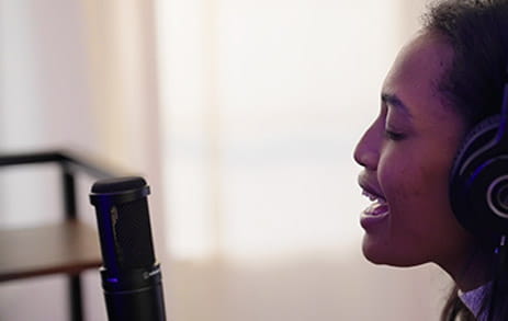 A profile view of stroke survivor, Chelsea, singing into a microphone