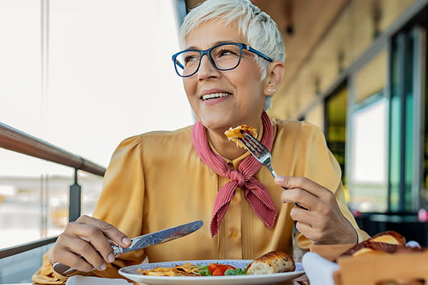Una mujer mayor sonríe mientras come una comida equilibrada. Una mujer mayor sonríe mientras come una comida balanceada.