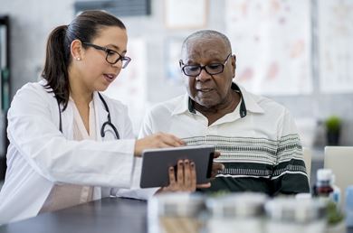 a female health care professional is showing her Black male patient information on a tablet a female health care professional is showing her Black male patient information on a tablet