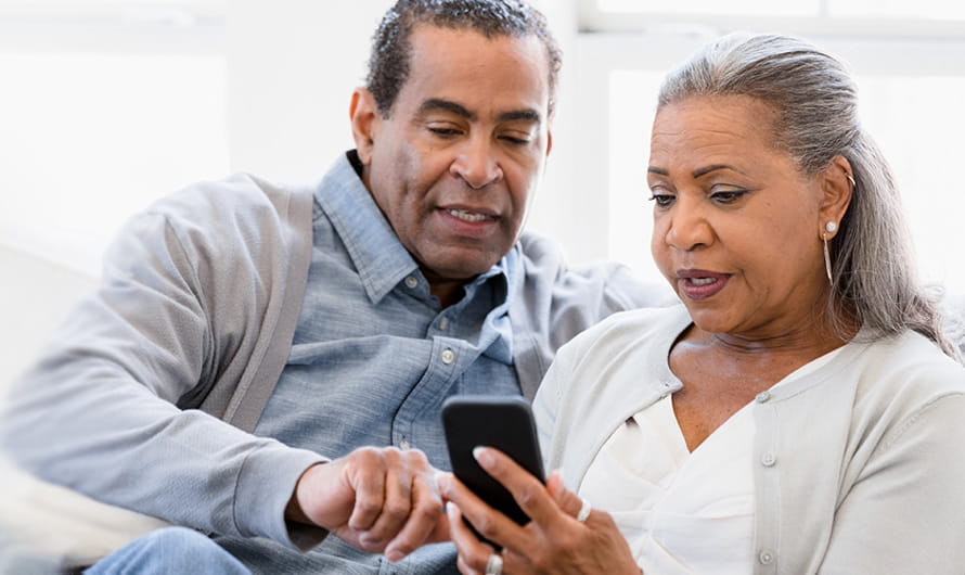 An older man and woman are looking at a smartphone. An older man and woman are looking at a smartphone.