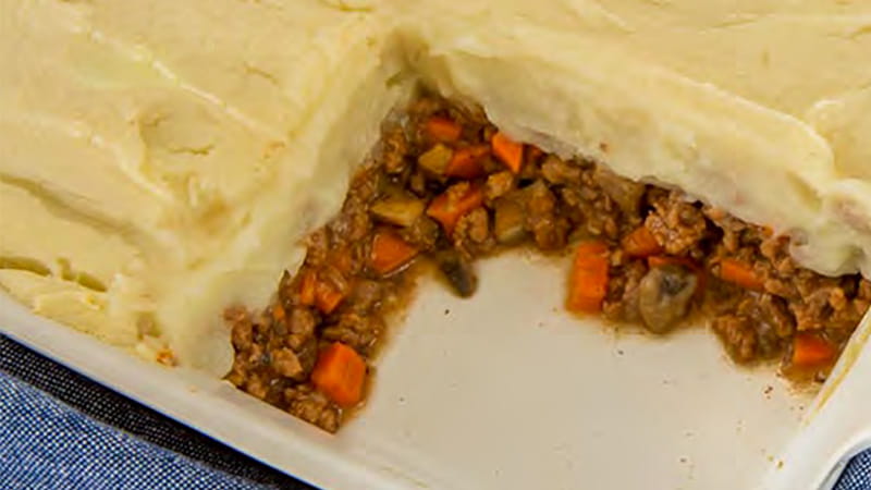 A Shepherd's Pie is in a casserole dish with a serving cut out showing the layers of meat and pastry top. A Shepherd's Pie is in a casserole dish with a serving cut out showing the layers of meat and pastry top.