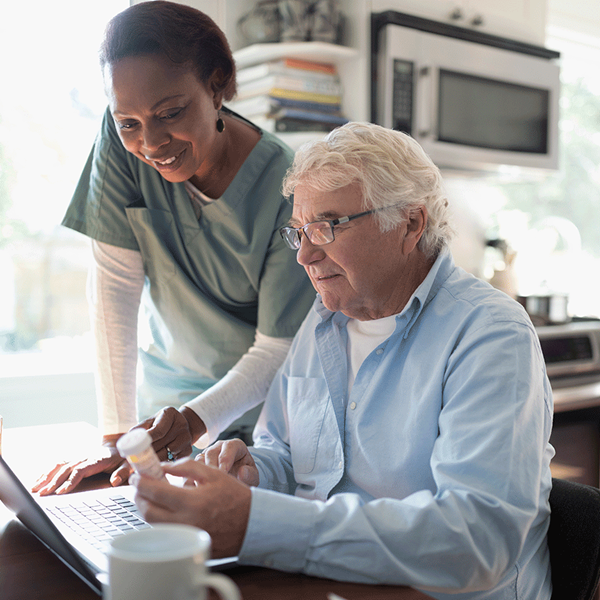 A healthcare worker and her patient are looking at a laptop. A healthcare worker and her patient are looking at a laptop.