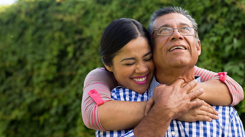 Young adult daughter embracing mature father and smiling. Young adult daughter embracing mature father and smiling.